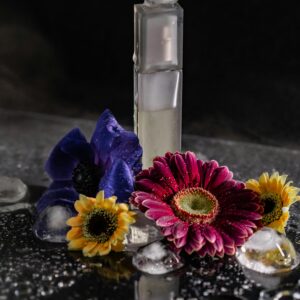 Stylish perfume bottle surrounded by colorful flowers and water droplets, captured in a studio setting.